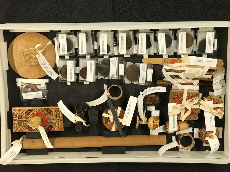 A group of different museum objects packed together in a plastic box.